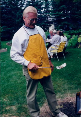 Lester Olfert, foreign secretary, with apron near barbecue