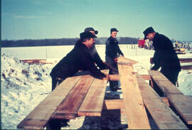 Barn raising crew cutting lumber for siding