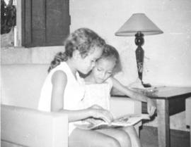 Two small girls looking at a magazine they