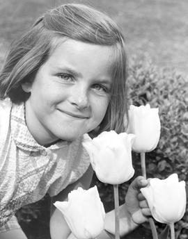 A young girl is posing next to some tulips. Head