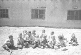 Children sitting on the ground eating watermelon