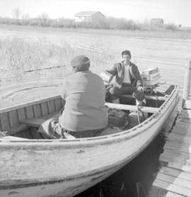 Two men departing by motorboat