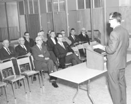 Roy Vogt behind a lecturn at a meeting where John H. Yoder spoke to Mennonite pastors