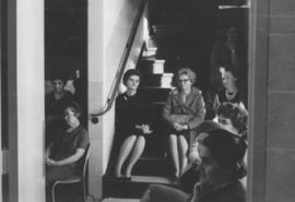 Women on the stairs listening at the first women's meeting at MCCO