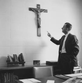 Harvey Taves points to crucifix  at new MCC offices