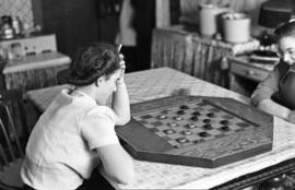 Two unidentified women playing checkers at a table