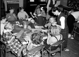 Girls doing crafts at a table in the Goodwill Hall, in Kitchener, Ontario