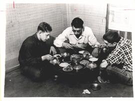 Valentine Yutzy, Woodrow Ramseyer, and Howard Burkholder eating in a traditional Korean manner at...