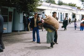 A man walks with a heavy burlap bag on his back in Dushanbe, USSR