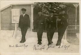 Four young men waiting outside a house in the snow