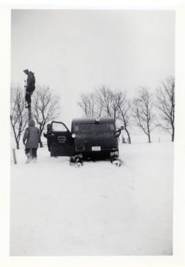 Men with a Manitoba Telephone System snowmobile