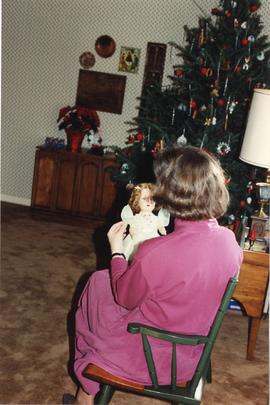 A woman looking at a doll.