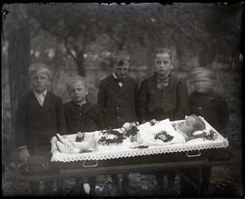 Five children standing behind an open casket