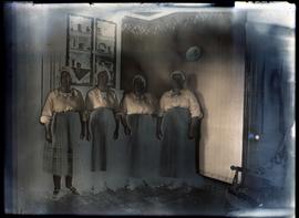 Interior portrait of four women standing in a corner of a house.
