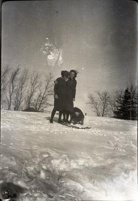Two girls on skis in the snow with their dog