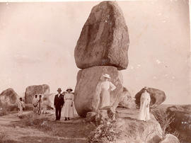 Eight unidentified people standing beside a rock formation typical of the Deccan plateau region